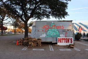 Patton's Christmas Trees sign with firewood and the iconic blue and white tent at Mockingbird & Abrams at Lakewood Village